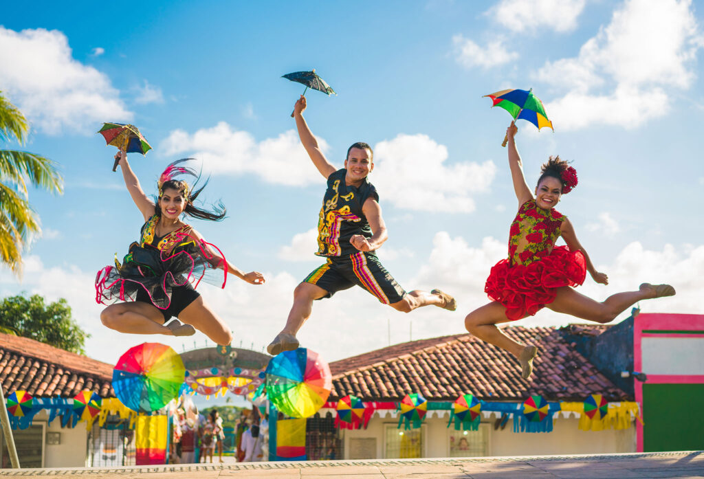 Carnaval dancers leap into the air with tiny umbrellas during the festival.