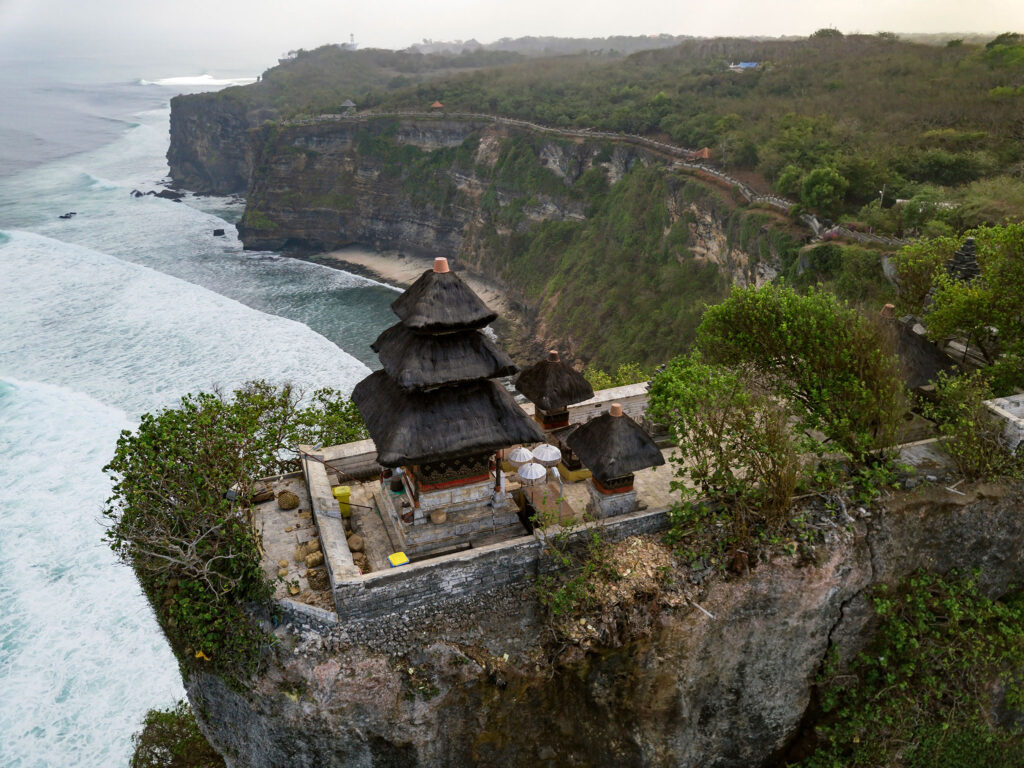A Hindu temple sits on a rocky outcropping above the ocean in Bali.