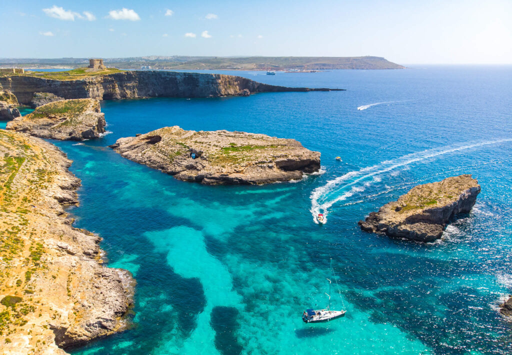 Boats explore the rocky coastline of Malta.