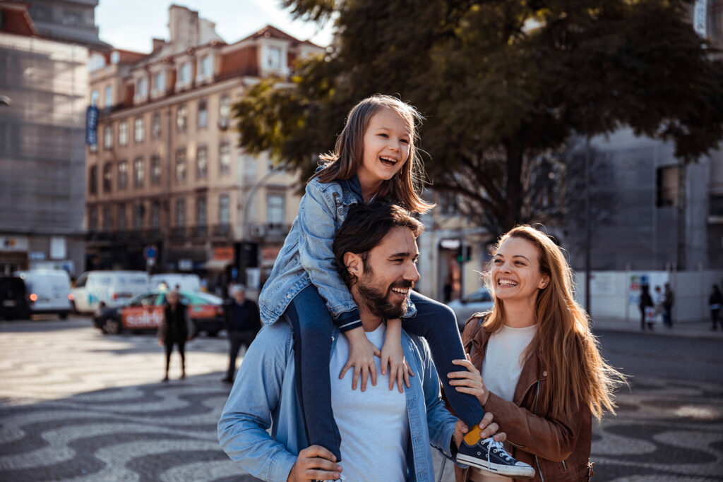 A young family laughs together as they walk through the city.