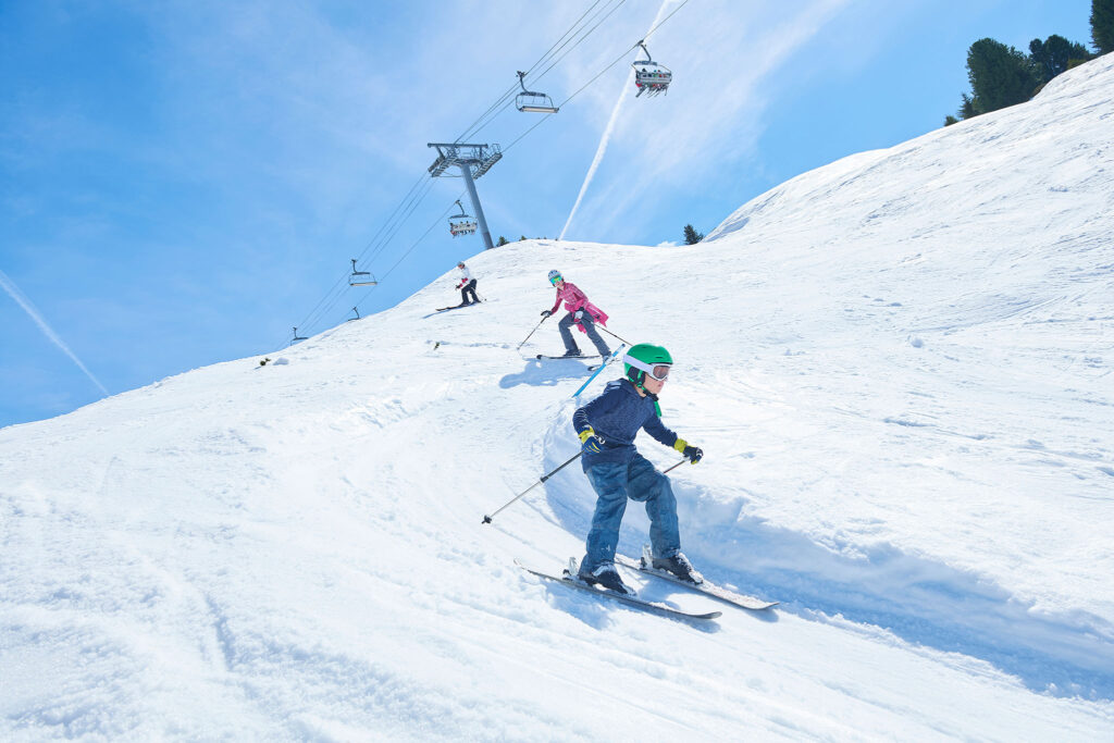 Kids swoosh under a ski lift in the Alps.