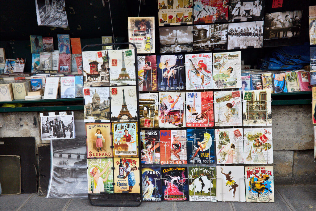 A street kiosk offers antique novels, vintage postcards, and old magazines on its bookshelves.