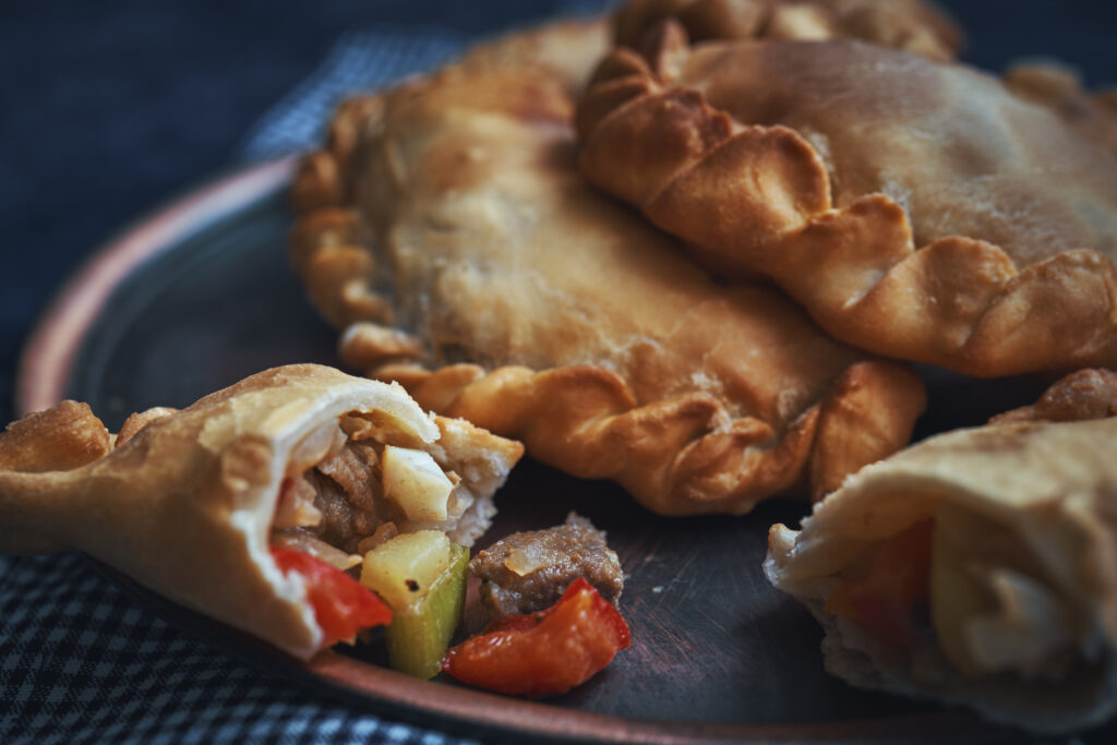 A wooden plate of Argentinean empanadas stuffed with meat and vegetables.