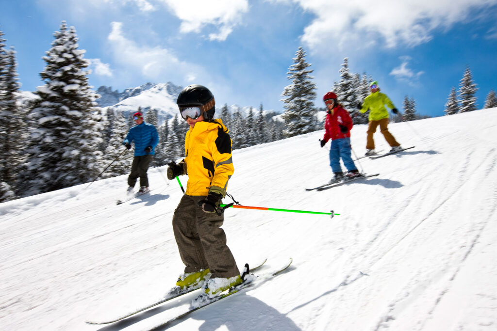 Eine Familie rauscht auf Skiern ins Tal.