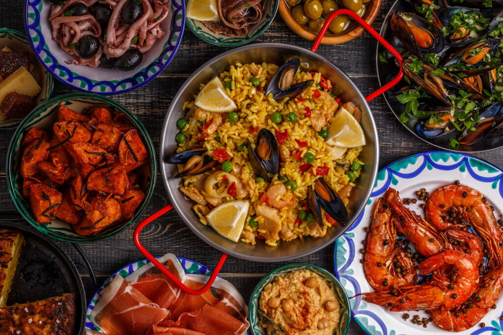 A colorful variety of paella and tapas on a dark wooden table.