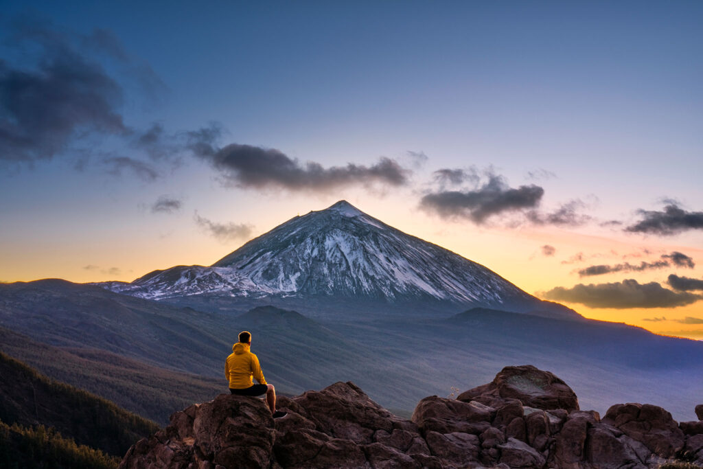 A man sits on a rock to gaze at Mount Teide in Teide National Park.