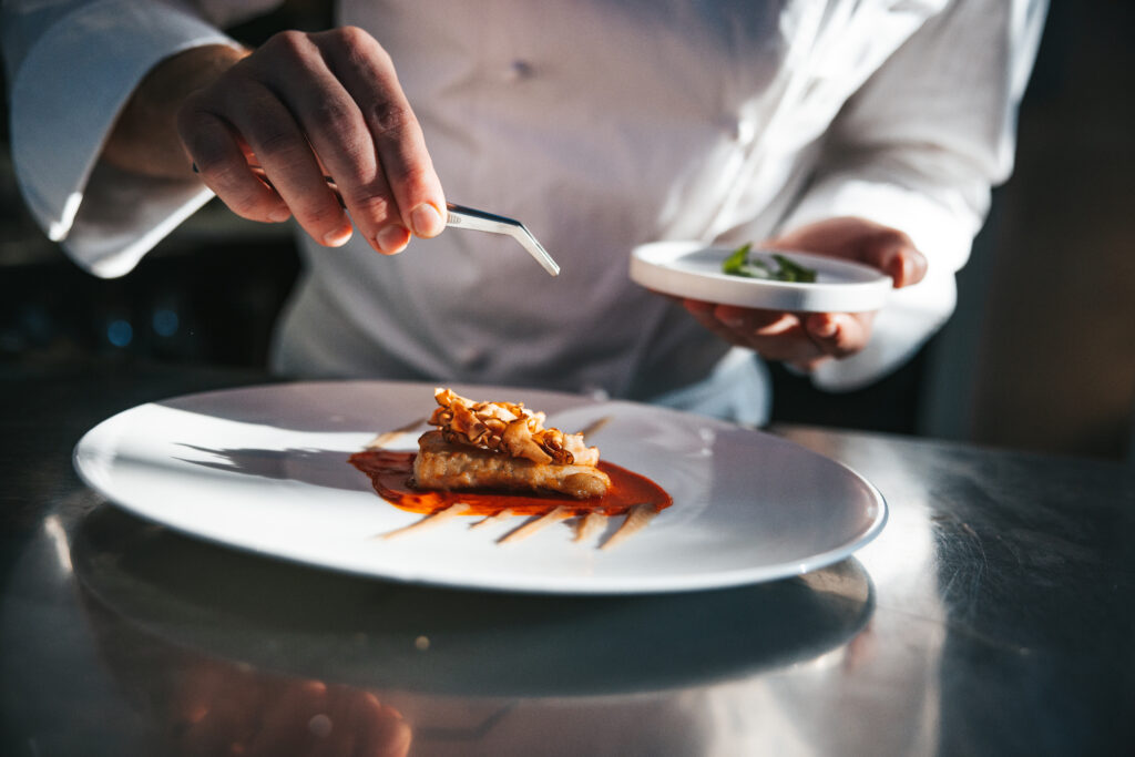 Chef preparando um prato com o peixe dourada em um restaurante de luxo, foto em close.